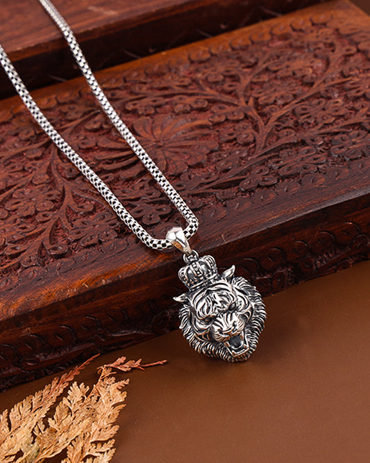 Silver necklace with a lion head pendant on a wooden surface
