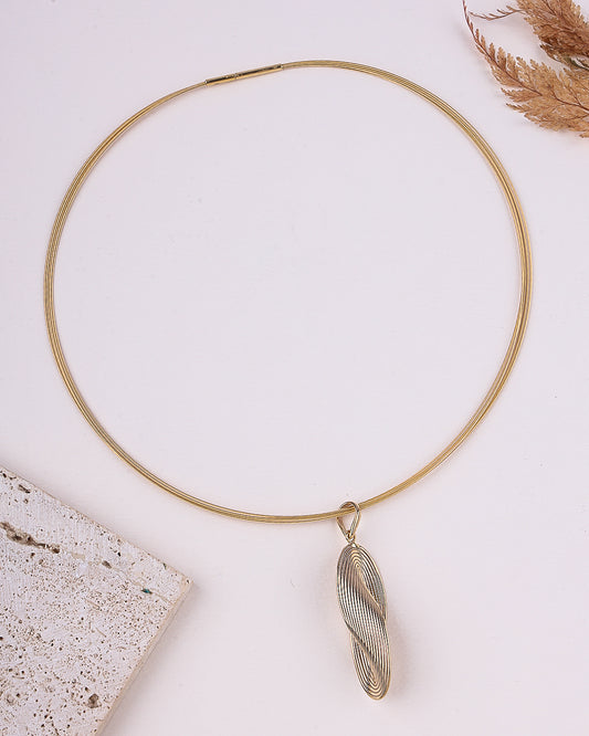 Gold necklace with a unique pendant on a light background
