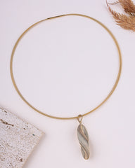 Gold necklace with a unique pendant on a light background