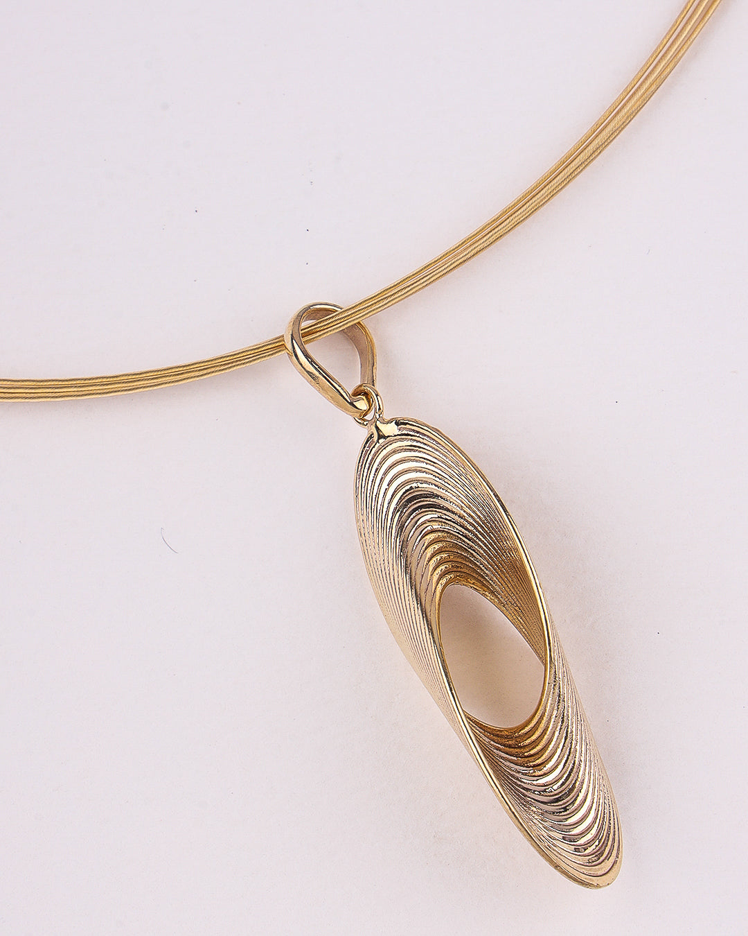 Gold necklace with a unique pendant on a light background