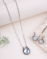 Necklace with a pendant on a light surface with a plant