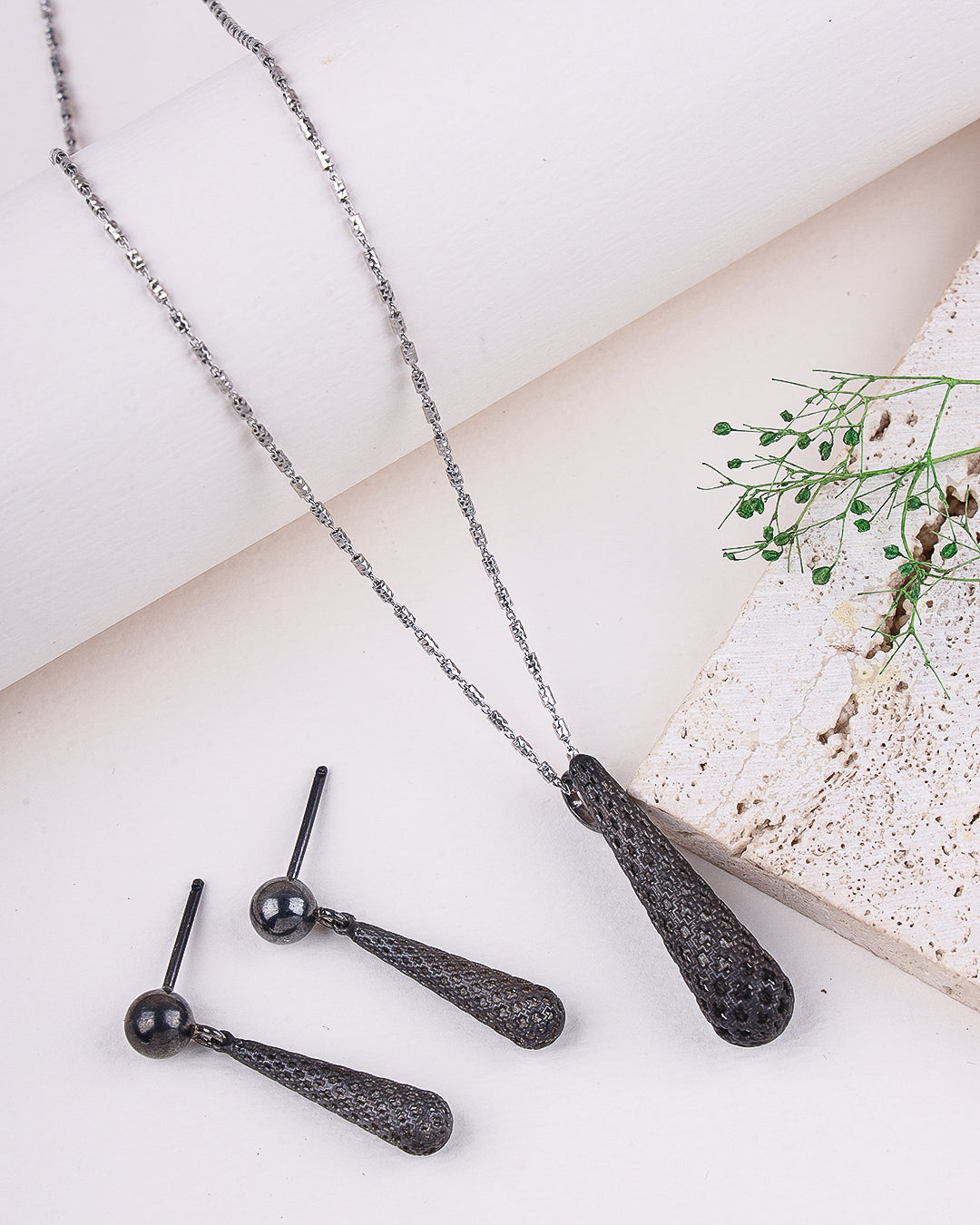 Black rhodium necklace with matching earrings on a light surface.