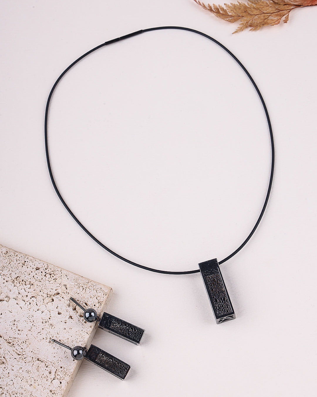 Black necklace with pendant on a light surface