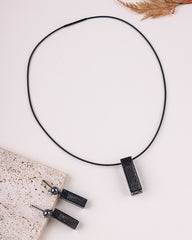 Black necklace with pendant on a light surface