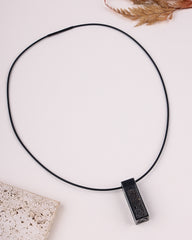 Black necklace with a pendant on a light surface
