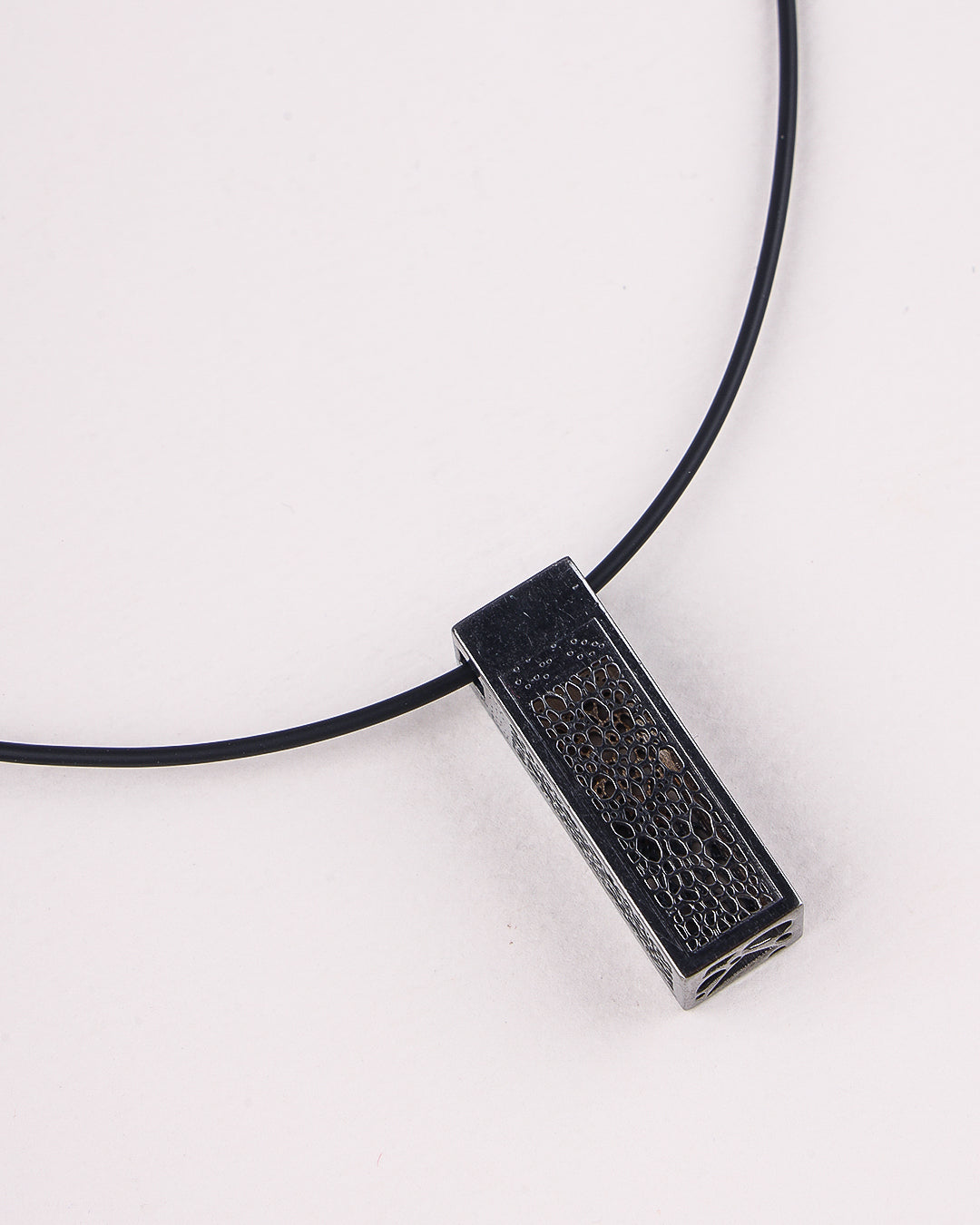 Black pendant on a black cord against a white background