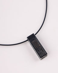 Black pendant on a black cord against a white background