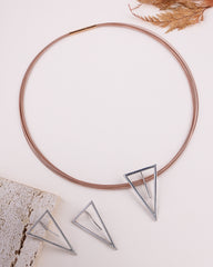 Rose gold necklace with triangle pendants on a light background