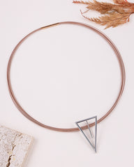 Rose gold necklace with a triangle-shaped clear stone on a light background