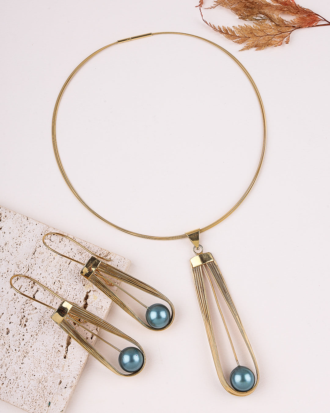 Gold necklace with pendant and matching earrings on a light background
