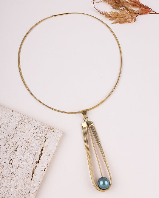 Gold necklace with a blue pendant on a light background
