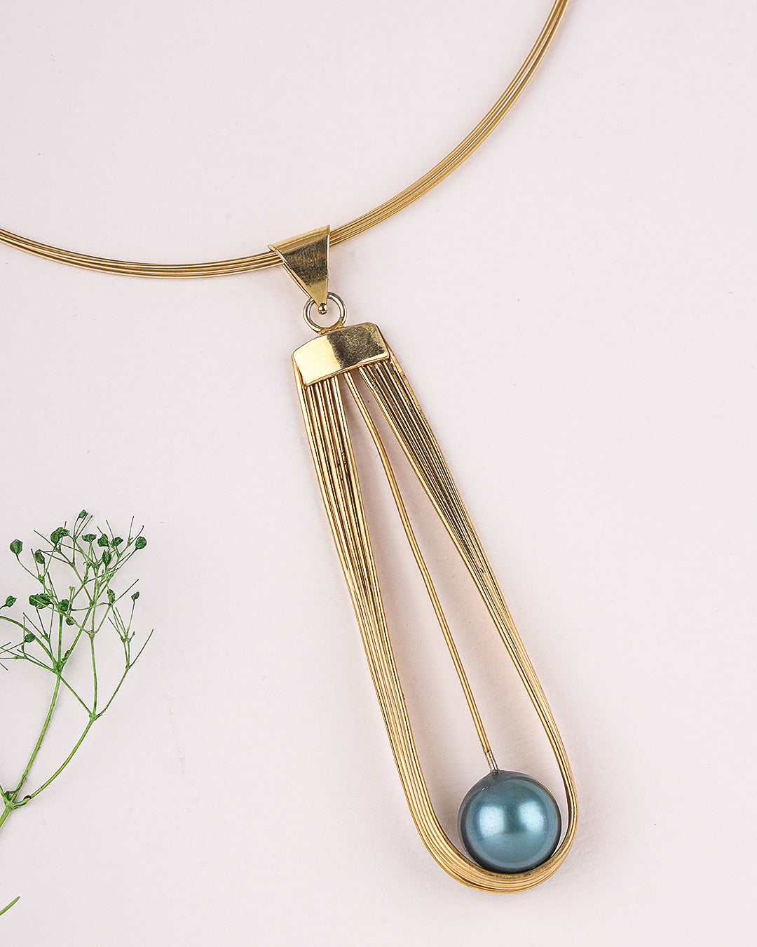 Gold necklace with a blue pendant on a light background