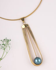 Gold necklace with a blue pendant on a light background