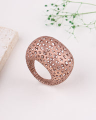 Rose gold ring object with intricate design on a light background
