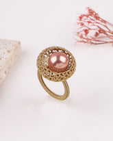 Gold ring with a pink pearl on a light background