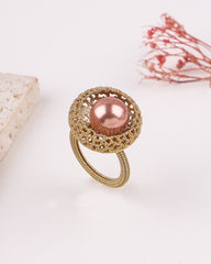 Gold ring with a pink pearl on a light background