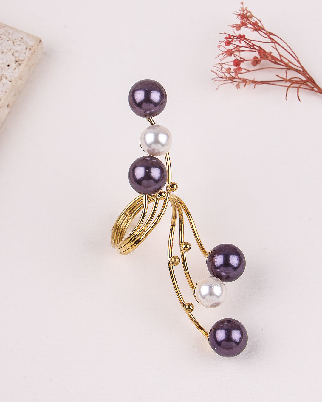 Gold ring with purple and white pearls on a light background