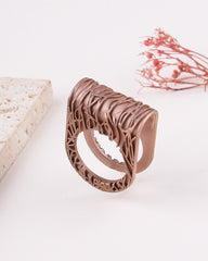 matte rose gold ring with intricate design on a light background