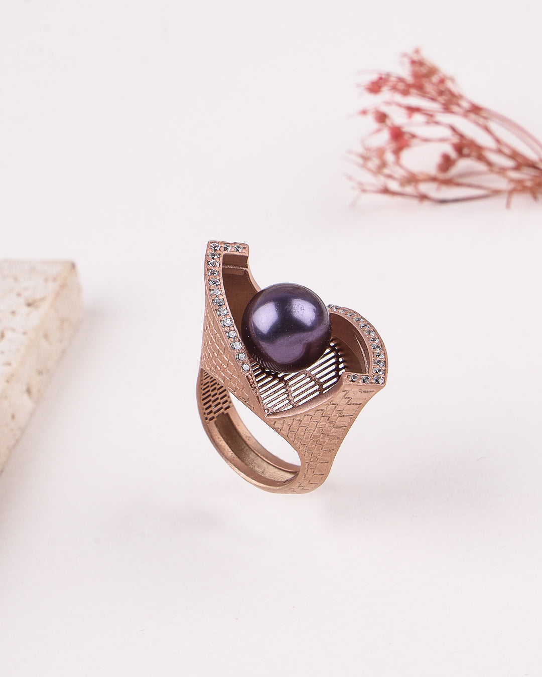 Rose gold ring with a purple gemstone on a light background