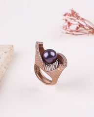 Rose gold ring with a purple gemstone on a light background