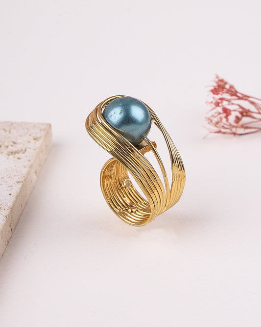Gold ring with a blue gemstone on a light background