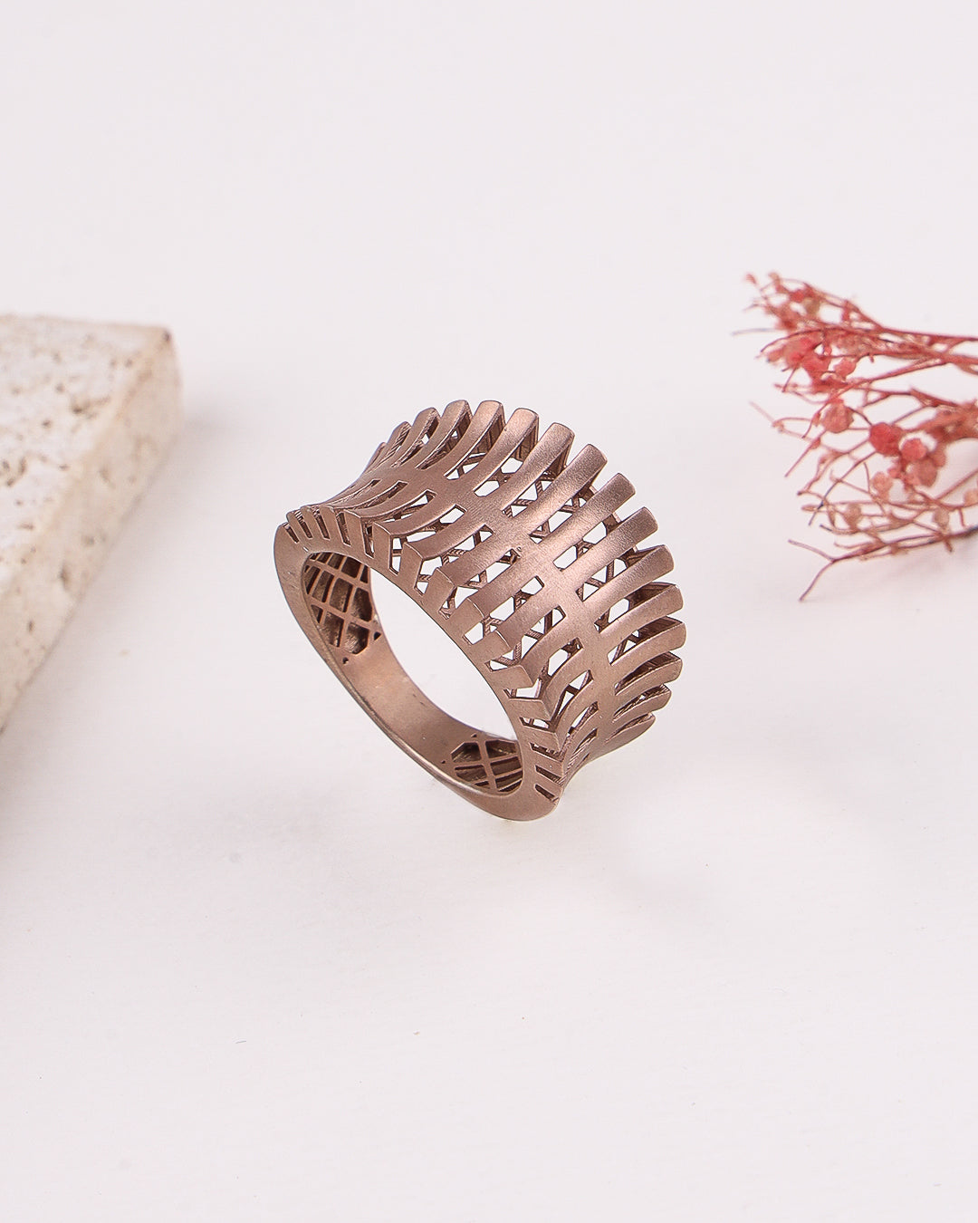 matte rose gold ring with intricate design on a light background