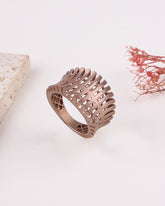 matte rose gold ring with intricate design on a light background