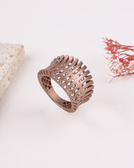 matte rose gold ring with intricate design on a light background