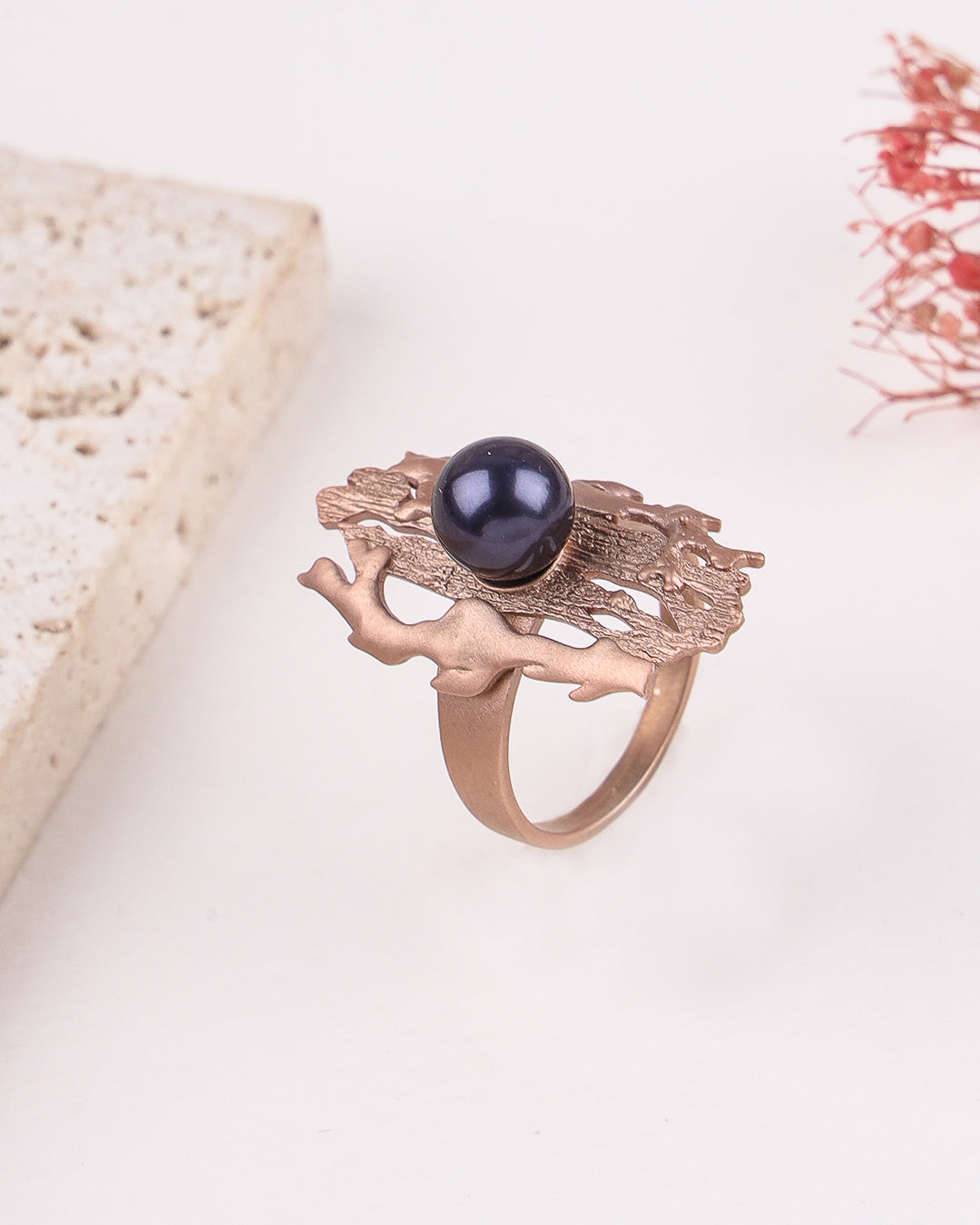 Rose gold ring with a black gemstone on a white background