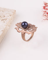 Rose gold ring with a black gemstone on a white background