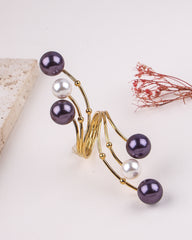 Gold ring with purple and white pearls on a light background