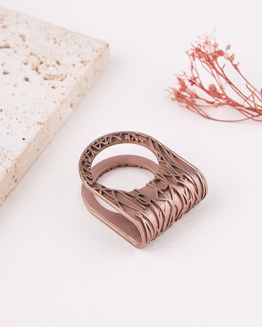 Rose gold ring with intricate design on a light background