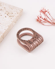Rose gold ring with intricate design on a light background