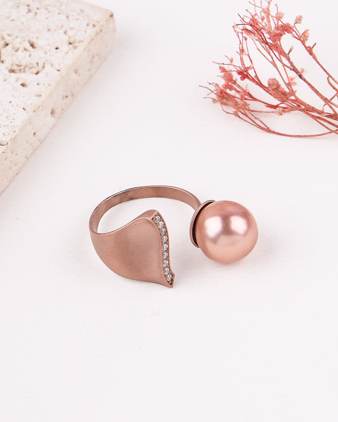 Rose gold ring with a large pearl on a light background
