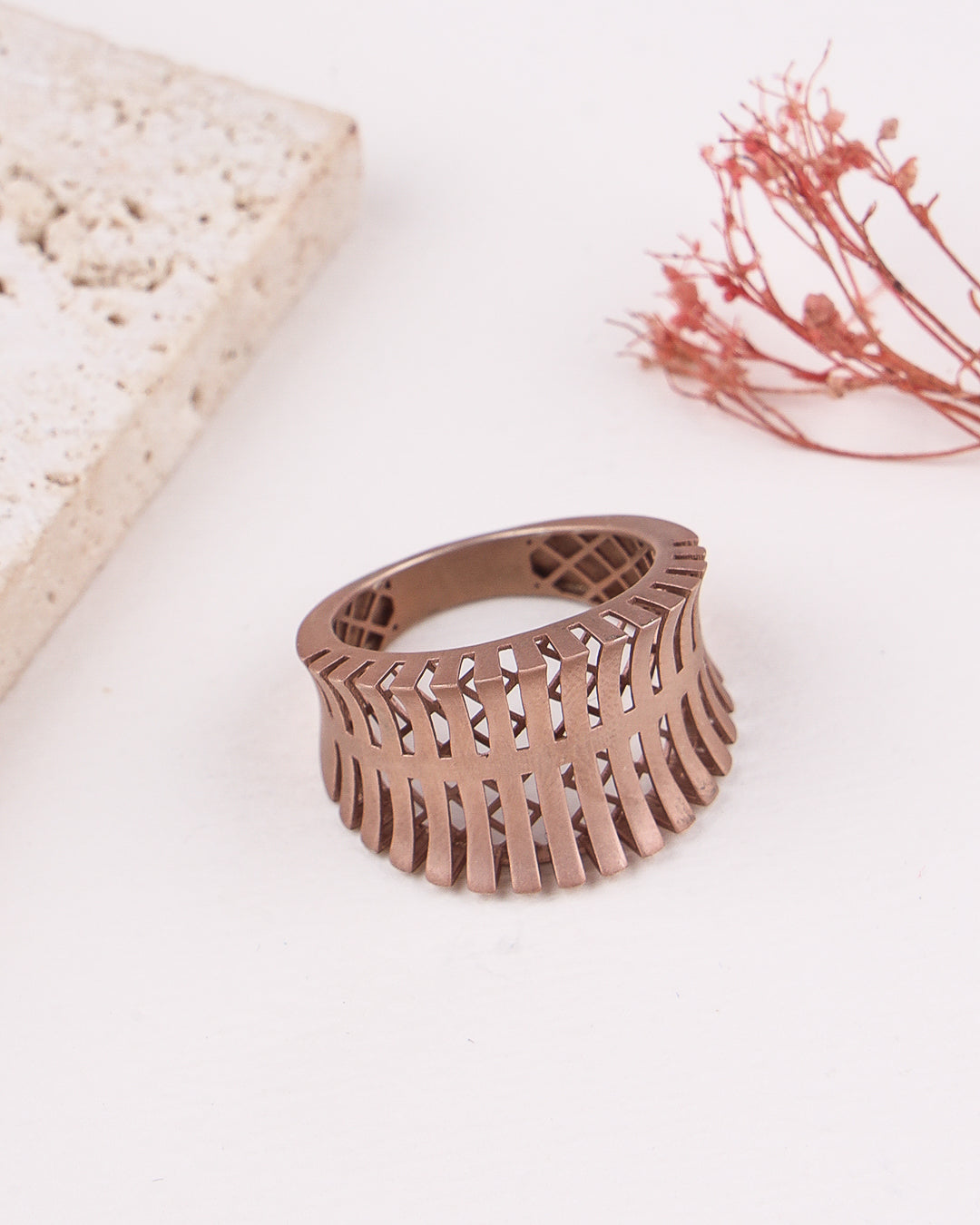 matte rose gold ring with intricate design on a light background
