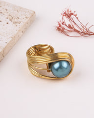 Gold ring with a blue pearl on a light background