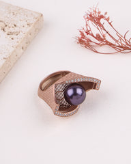 Rose gold ring with a purple pearl and diamond accents on a light background