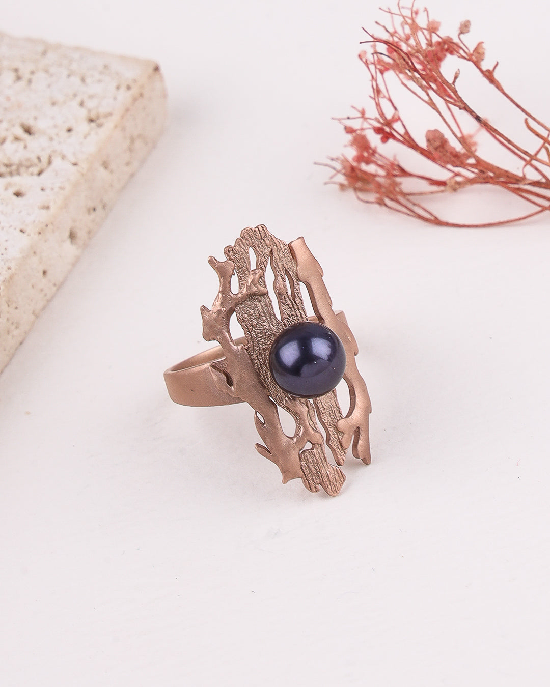 Rose gold ring with a black gemstone on a light background