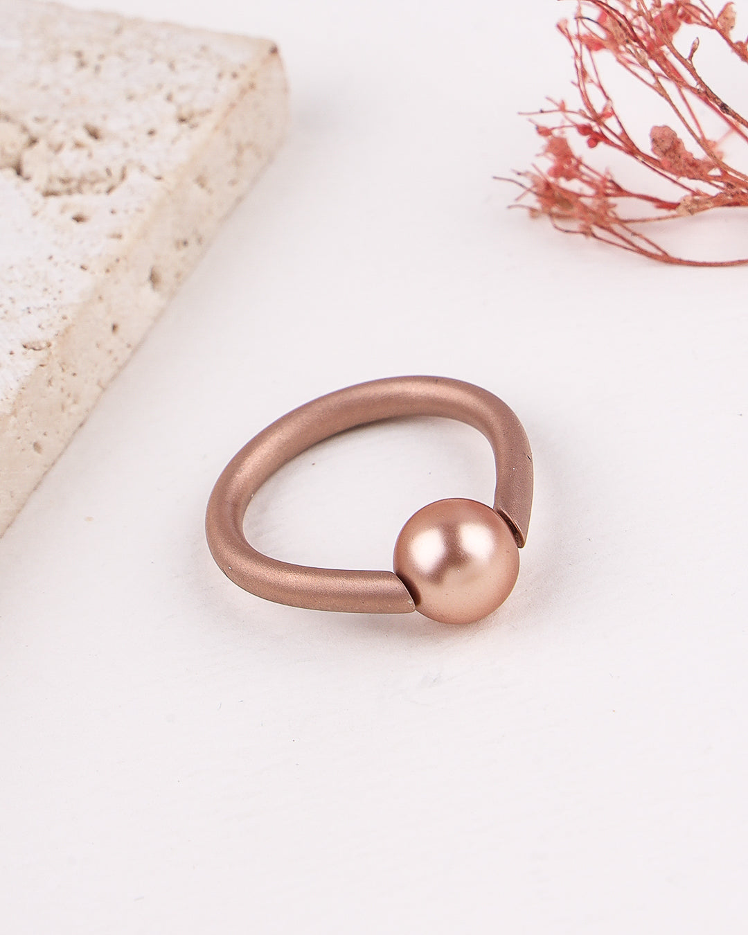 Rose gold ring with a spherical design on a light background