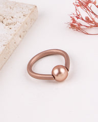 Rose gold ring with a spherical design on a light background
