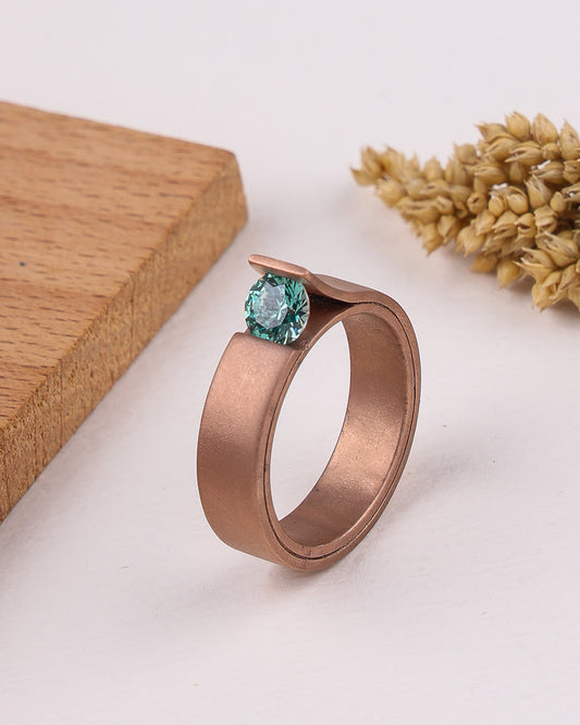 matte rose gold ring with a blue gemstone on a light background