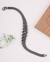 Black rhodium bracelet leash on a white background with a wooden block and greenery.