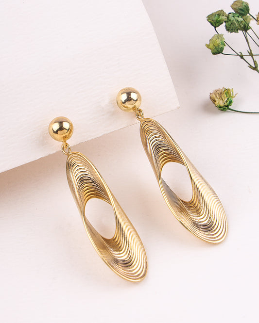 Gold earrings on a white surface with a blurred background