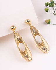 Gold earrings on a white surface with a blurred background