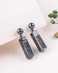 Pair of earrings with textured rectangular pendants and spherical tops on a light background.