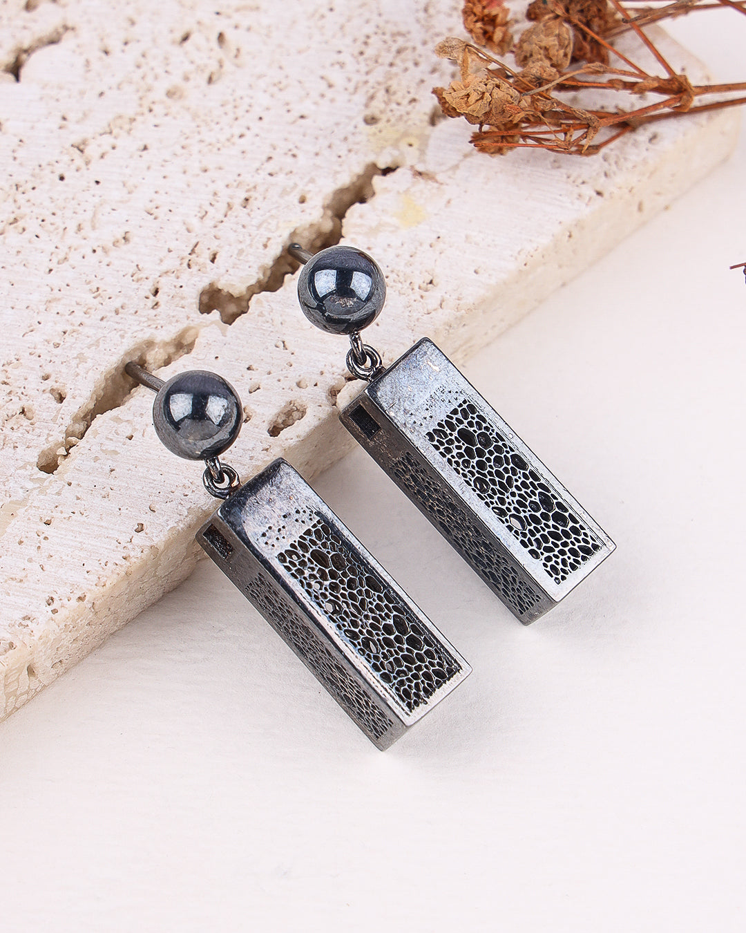 Silver earrings with textured design on a light background