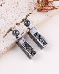 Silver earrings with textured design on a light background