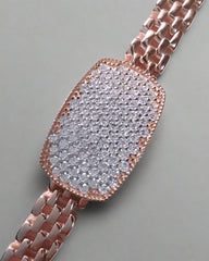 Rose gold watch with a diamond-studded face on a gray background
