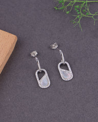Silver earrings with MOP on a dark surface with greenery