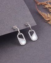 Silver earrings with a central MOP on a gray surface
